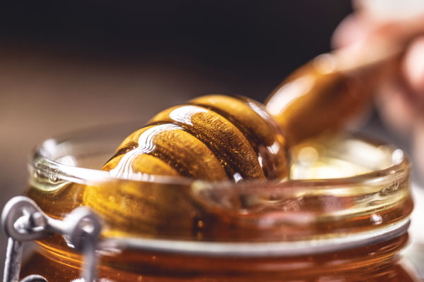 honey covering dipper in a jar